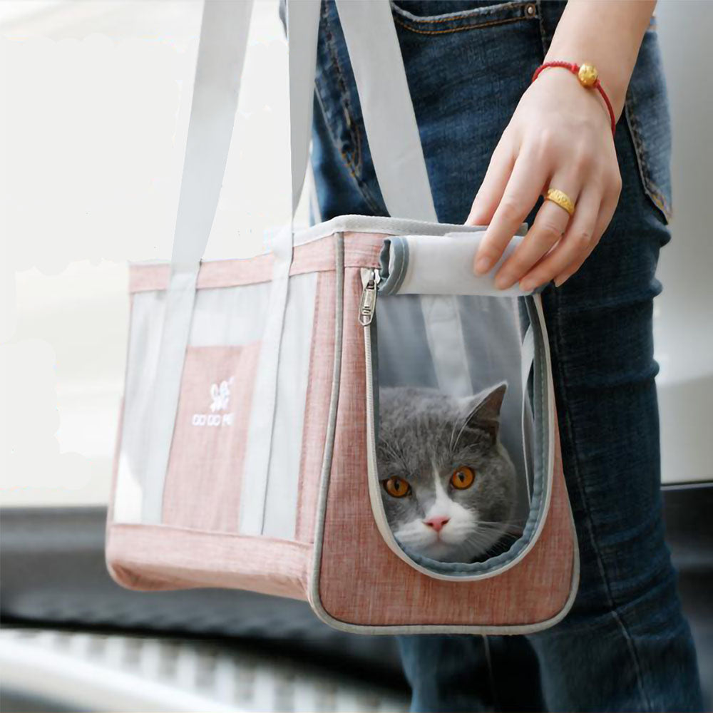 Gray cat peaking out of open zip opening to the Dodo Pet Tote Bag Carrier with handles being carried by human hand.