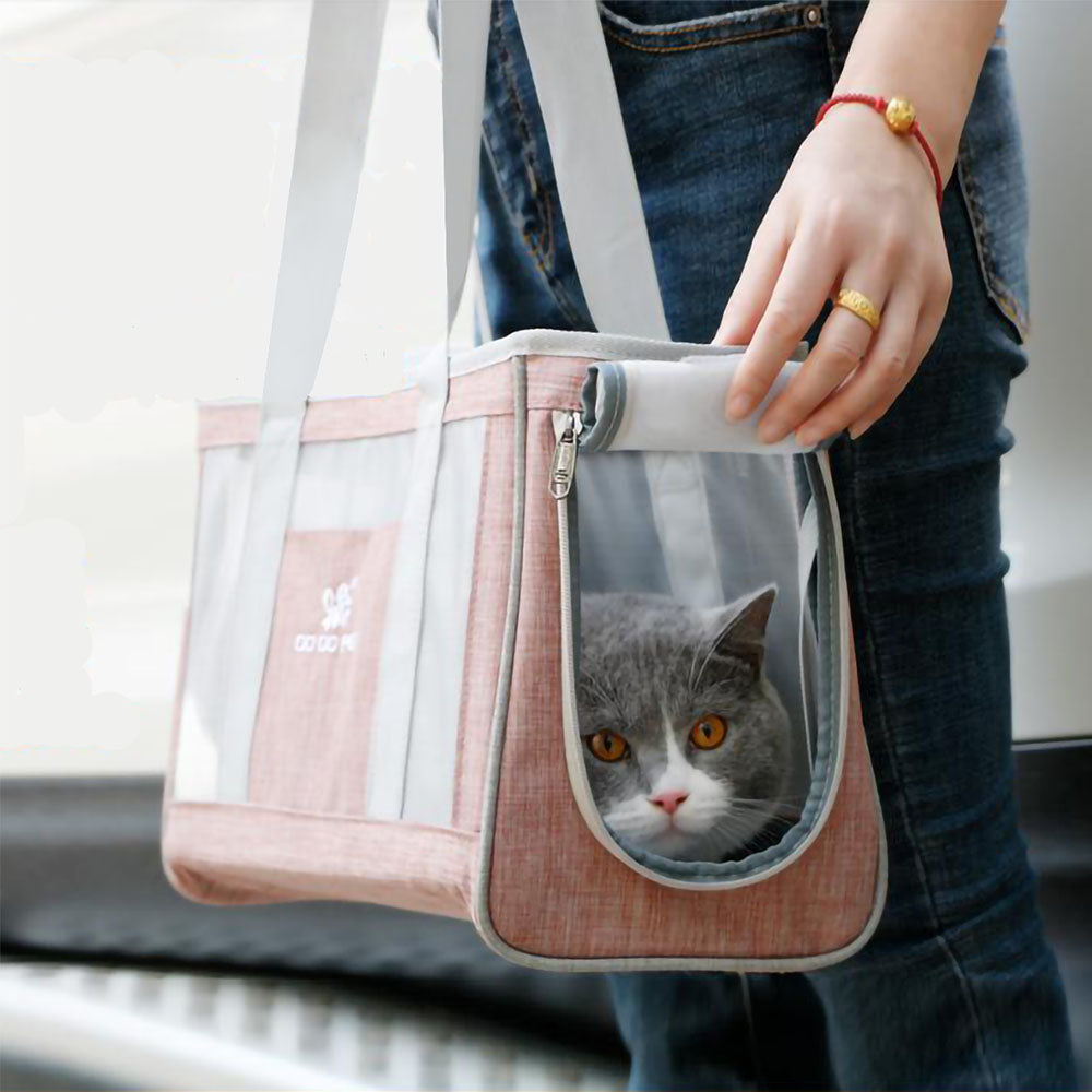 Gray cat peaking out of open zip opening to the Dodo Pet Tote Bag Carrier with handles being carried by human hand. 